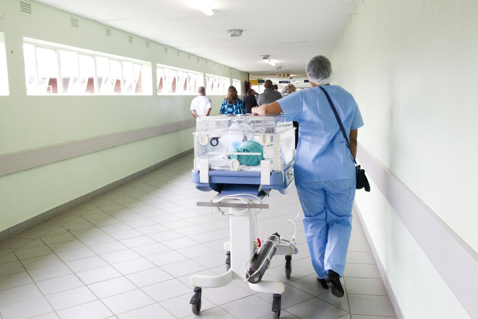 A nurse moving equipment along a hospital corridor