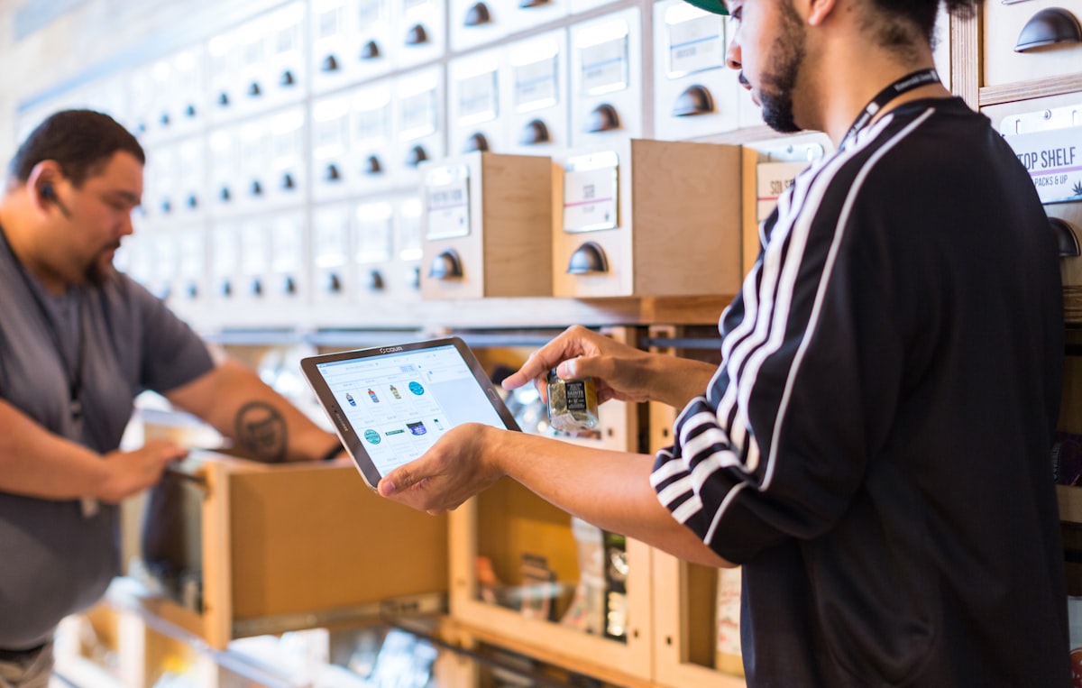 Warehouse operator tapping a tablet console while working at labeled stock shelving