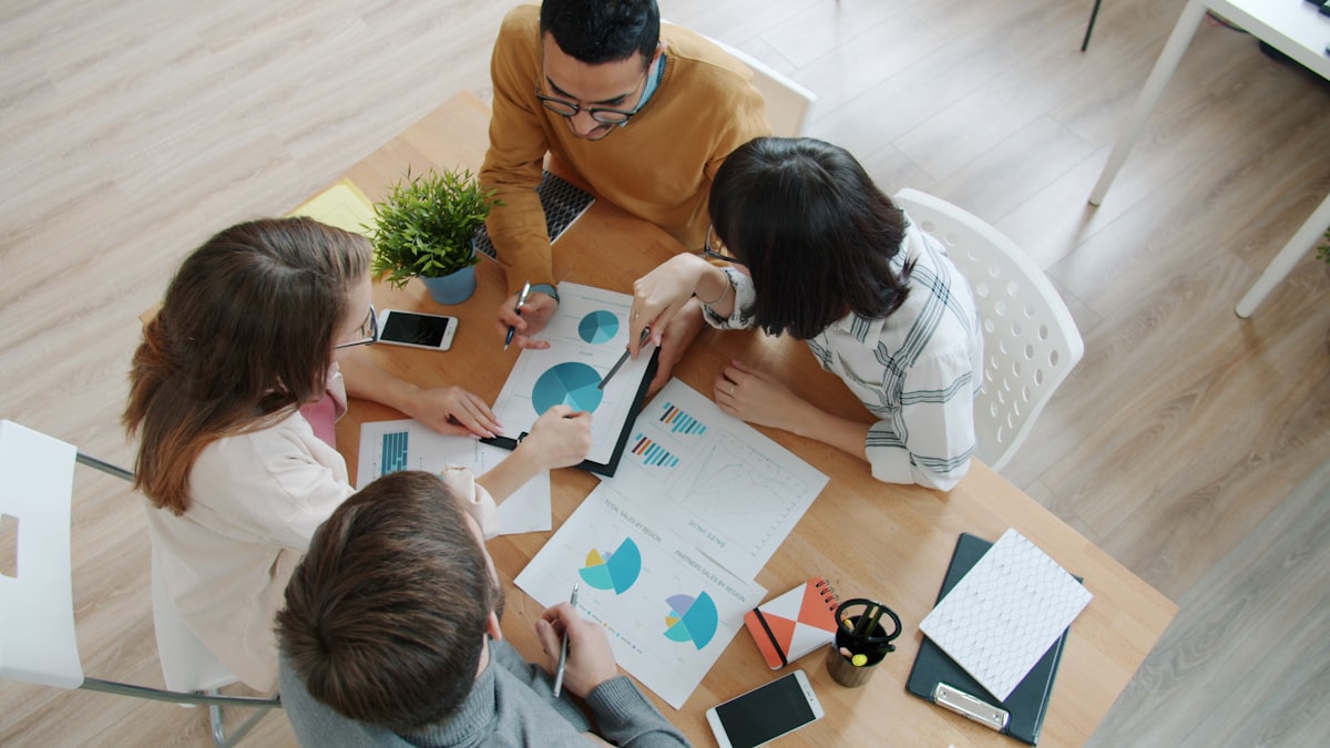 Team gathered around a table reviewing printed financial charts and reports during a month-end review